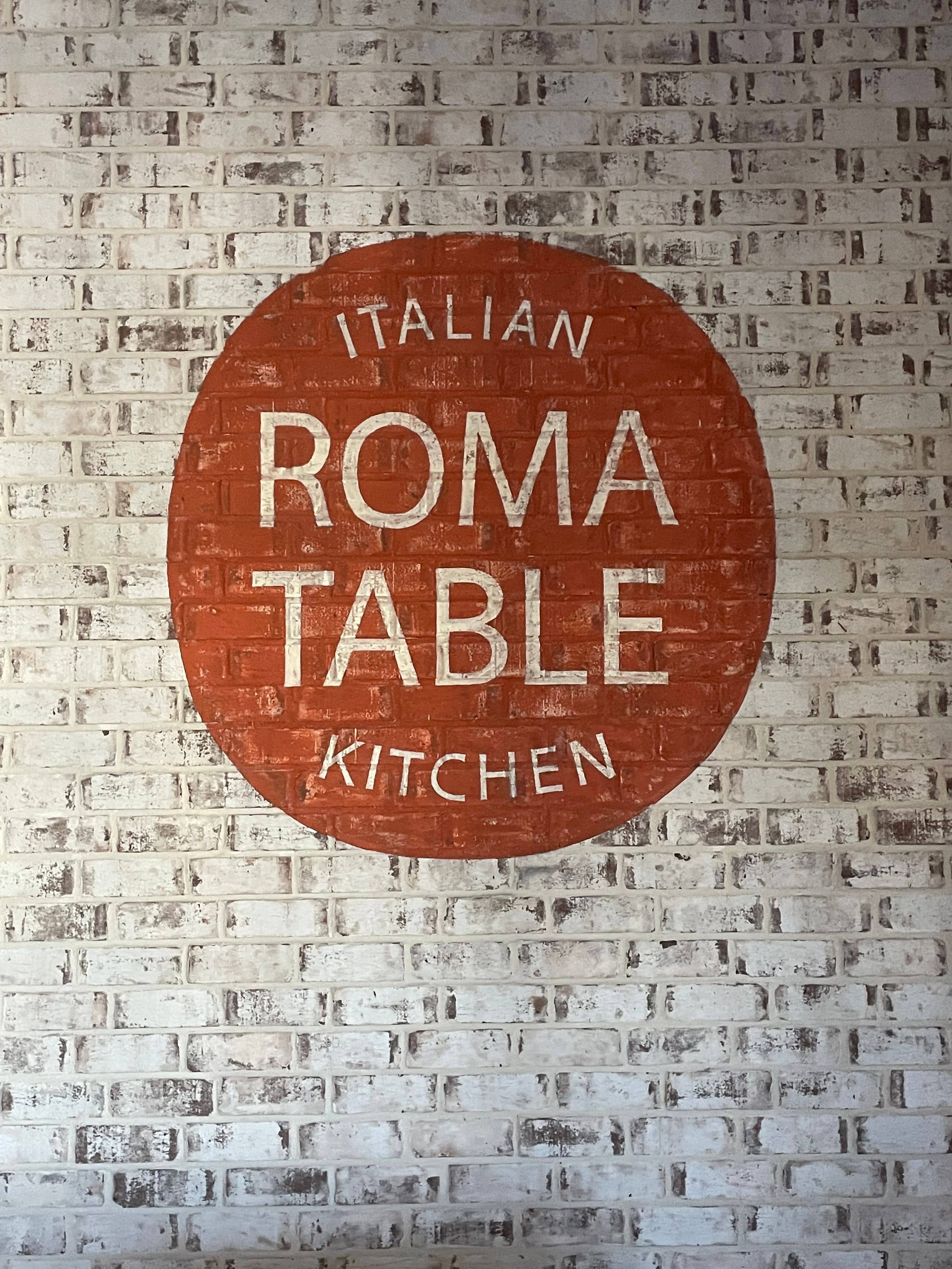 Restaurant logo for Roma Tabel painted on the interior brick located inside.