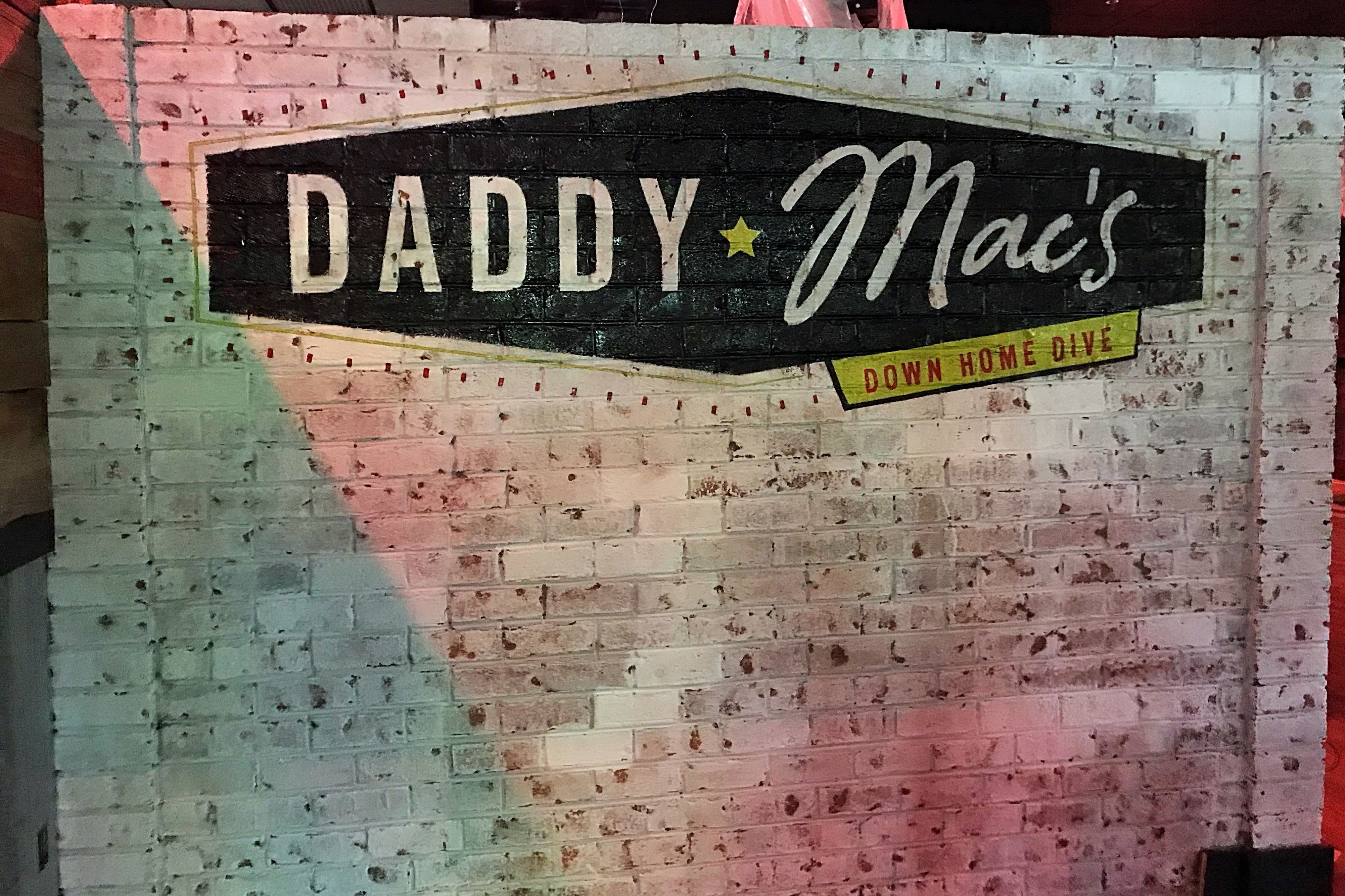 Painted sign on white washed brick for the restaurant Daddy Mac's Down Home Dive