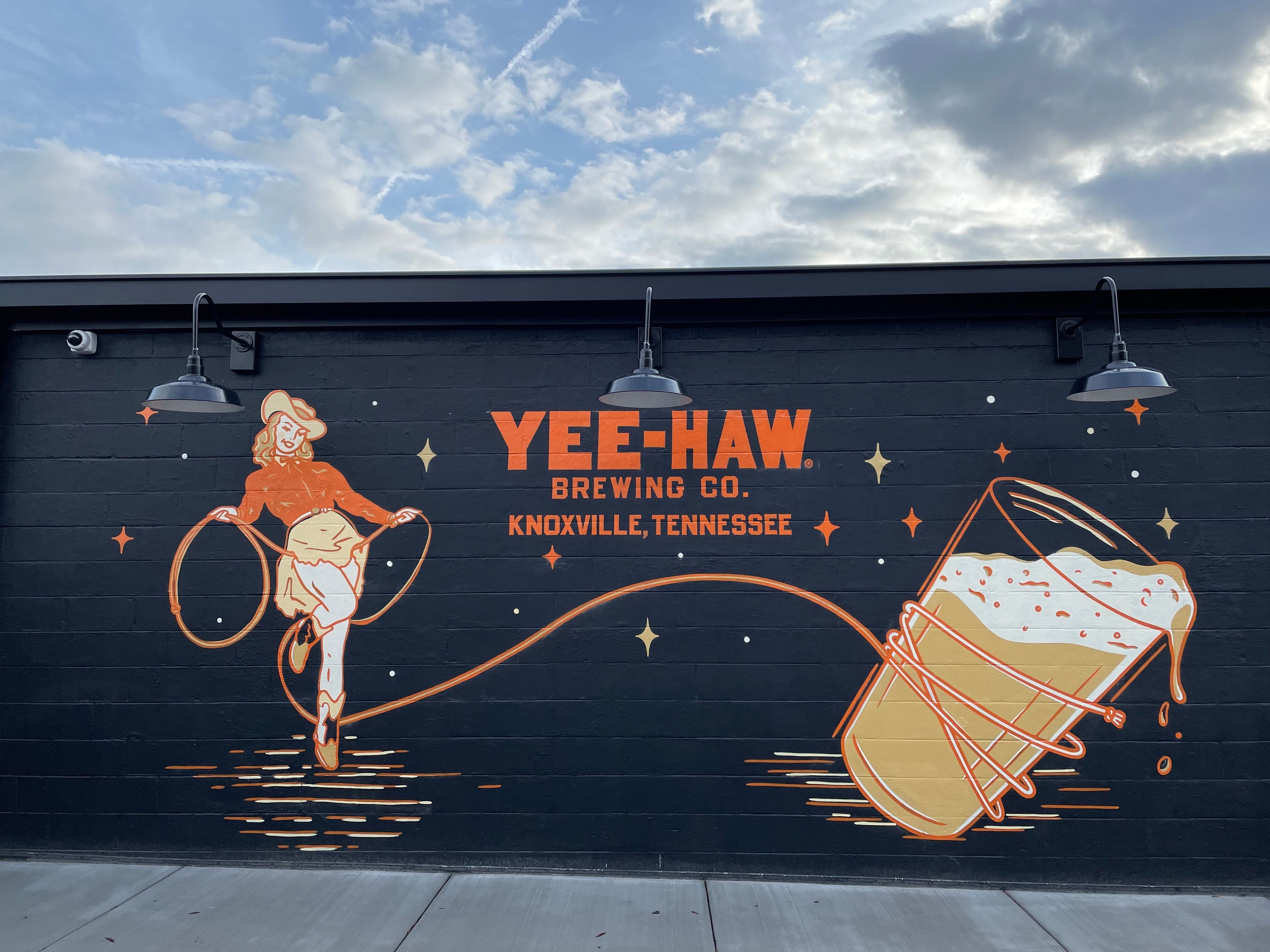 Painted Mural of beer logo on exterior stucco, Cowgirl roping a glass of beer at Yee-Haw Brewing Company, downtown Knoxville, TN @coultersigns @yeehawbrewing