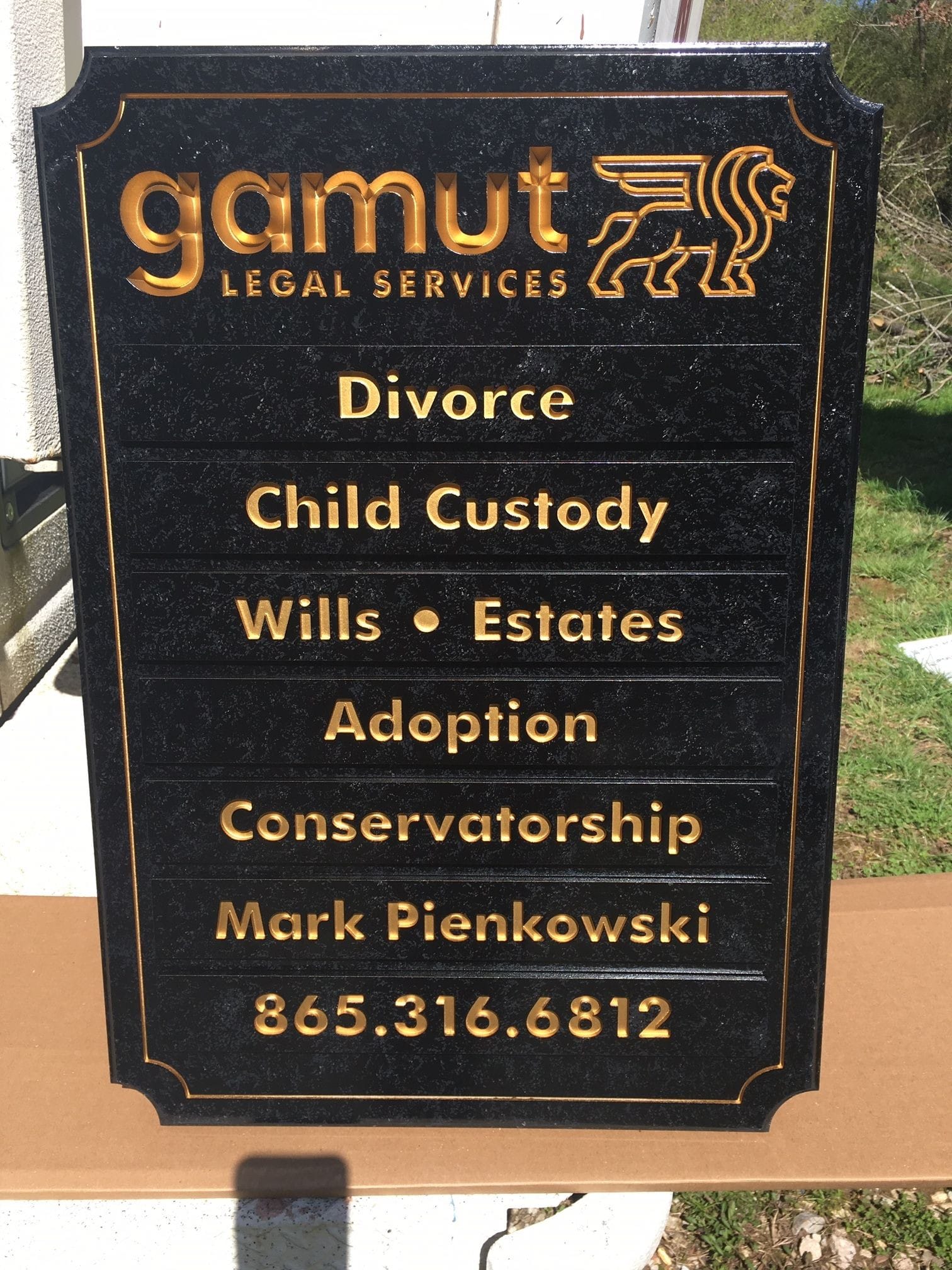 This routed sign is painted to to look like black and grey granit with imitation gold